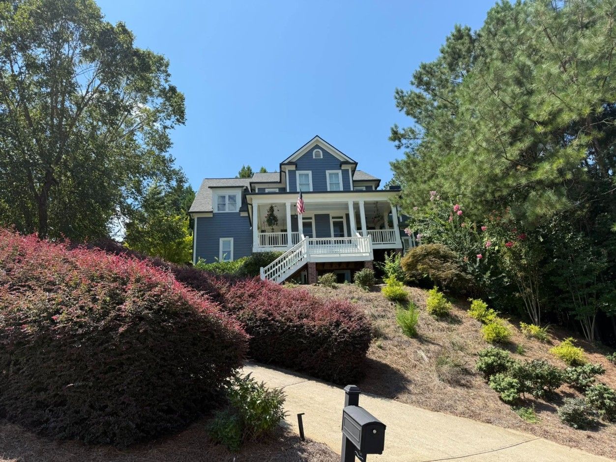 Blue two-story hillside home with white porches