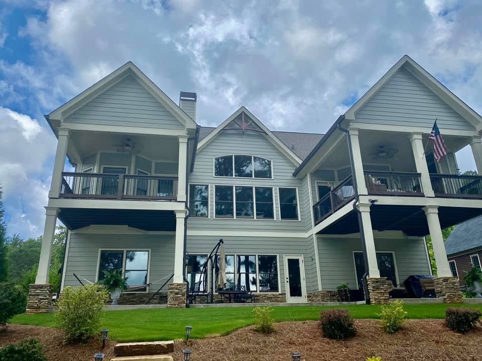 Lake home with green-gray siding and two levels of white covered porches