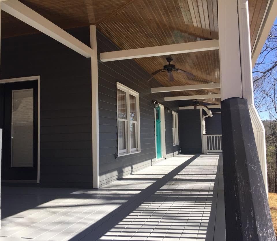 Covered mountain-home porch with charcoal siding, white trim, painted floor and teal front door
