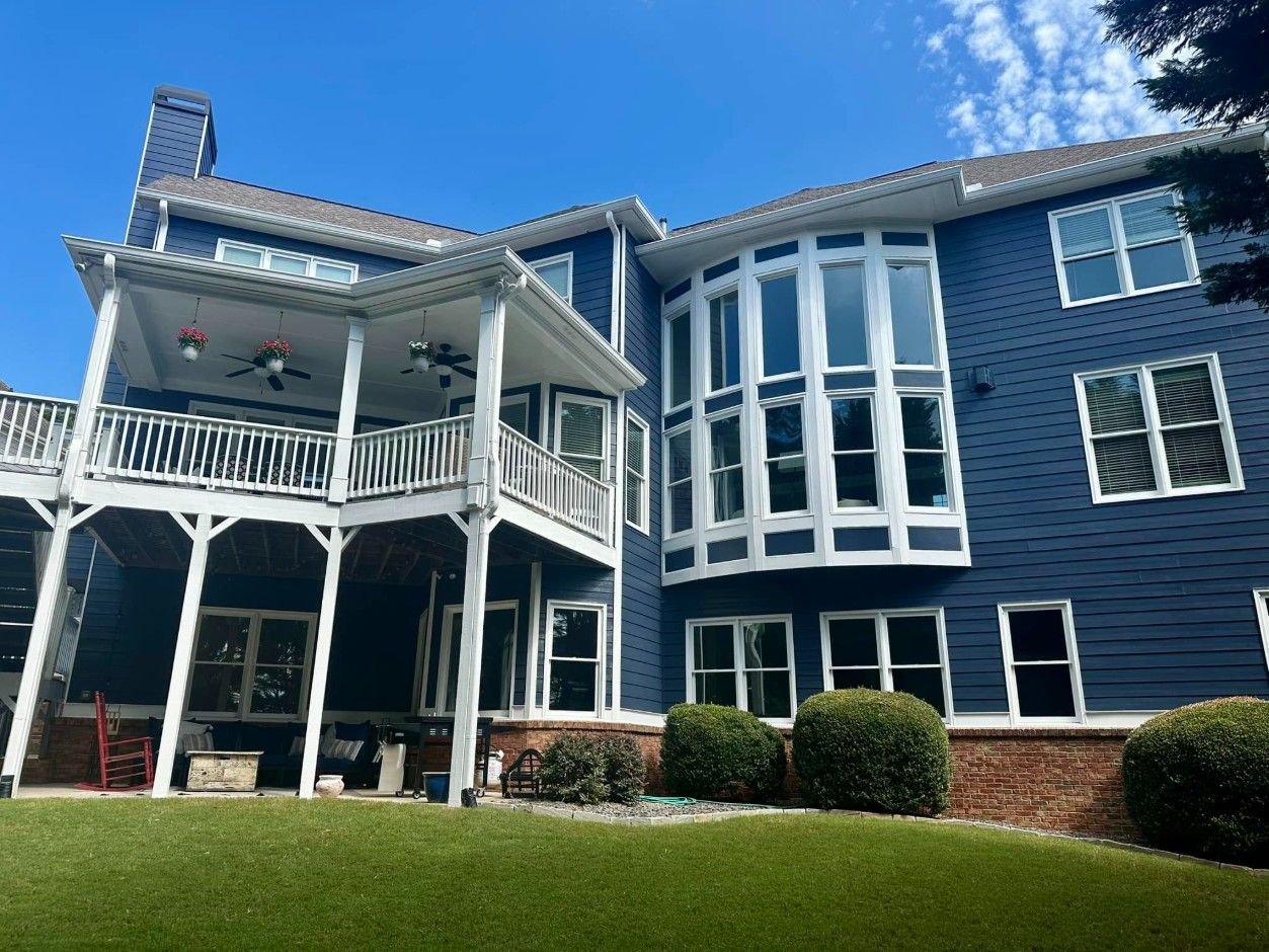 Navy-sided home with white trim, bay windows and covered porches