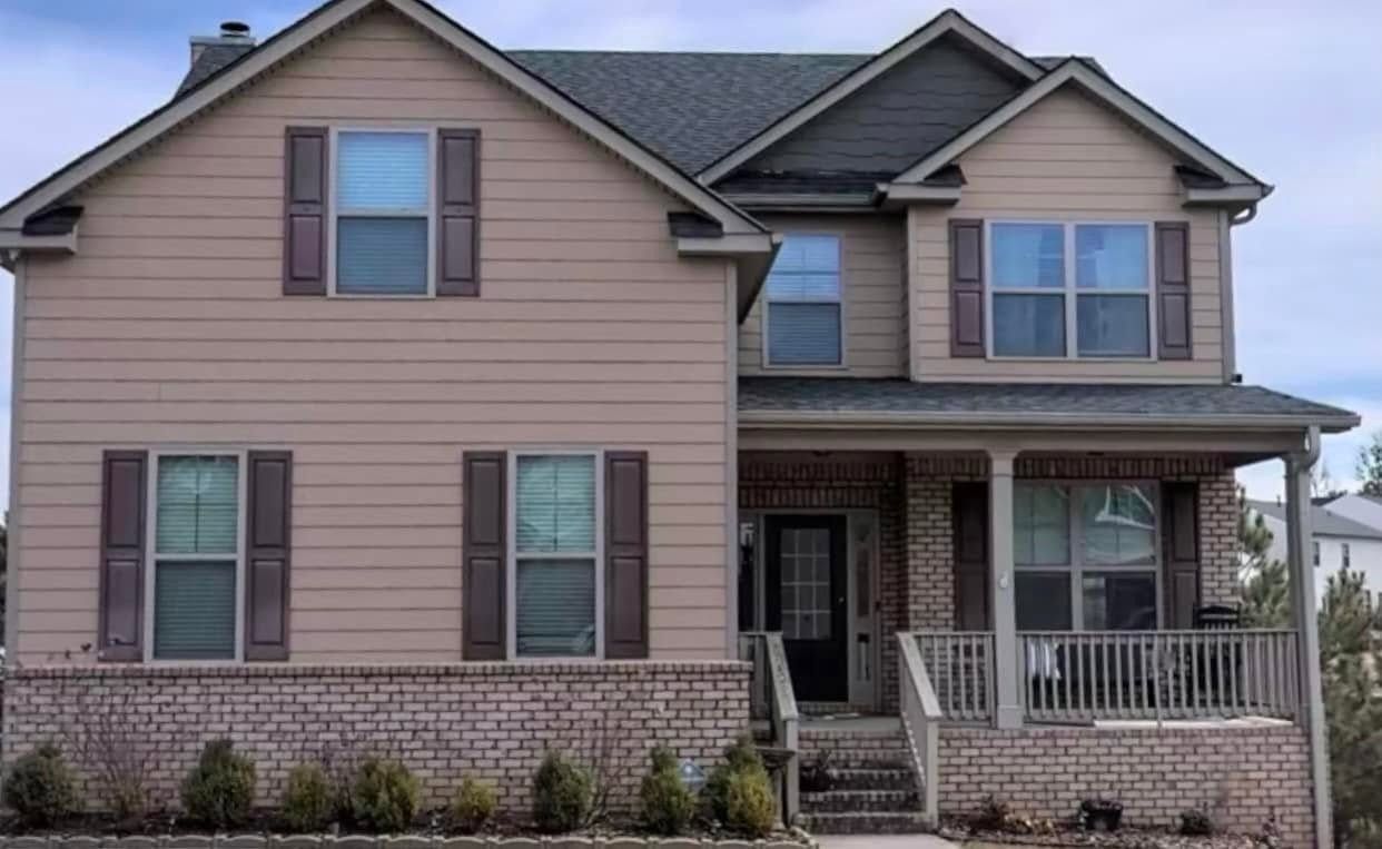 Two-story home with tan siding and plum shutters over brick