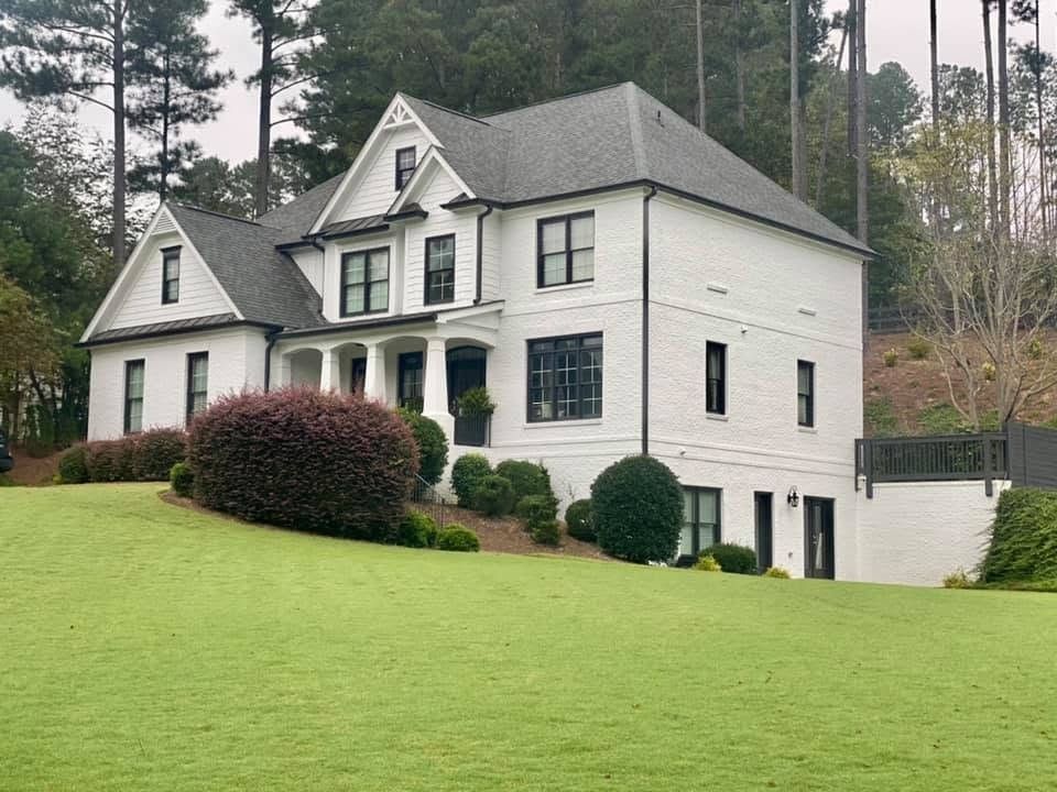 White painted brick home with black windows on a hillside lot