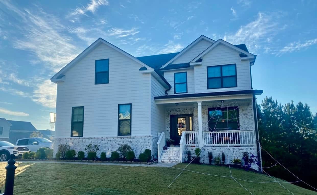 White two-story home with black windows and painted brick